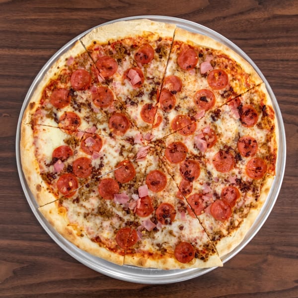 A whole meat lover's pizza with pepperoni, ham, and sausage, sliced on a metal pan.